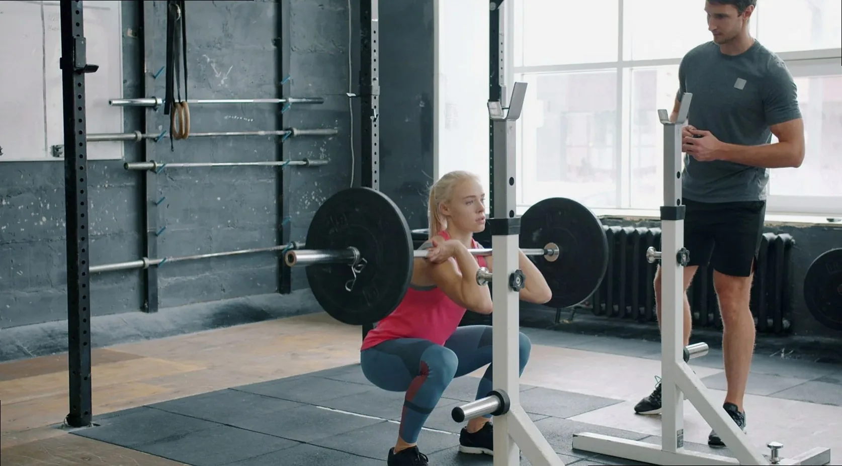 Member squatting with a coach spotting from behind