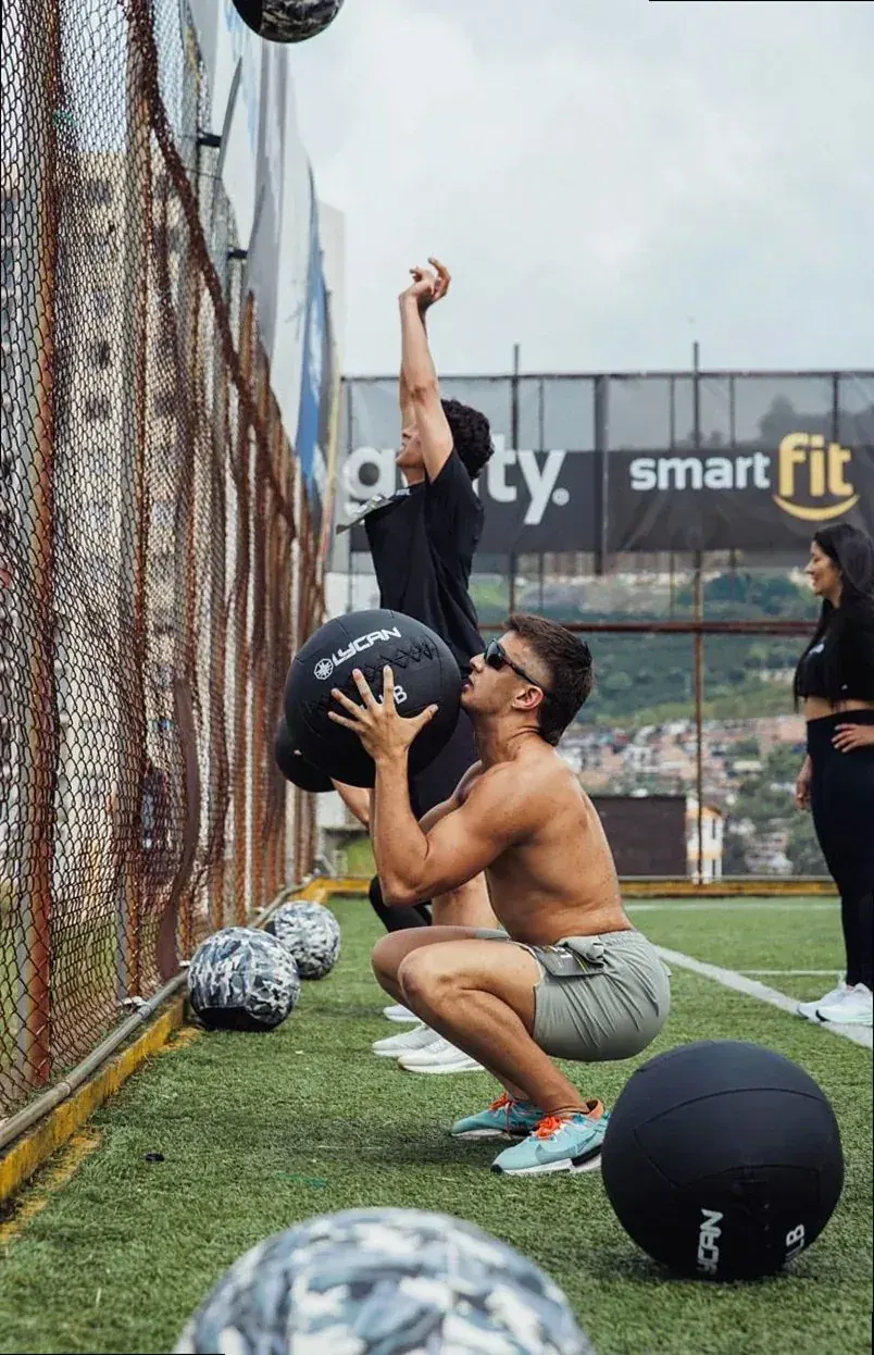 Member throwing a medicine ball against a fence outside
